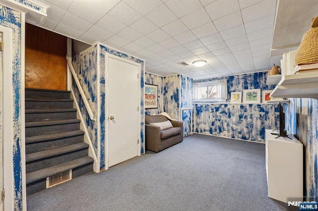 below grade area featuring carpet floors, visible vents, stairway, and wallpapered walls