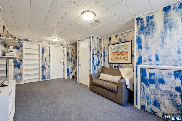 sitting room with carpet flooring, visible vents, wallpapered walls, and stairs