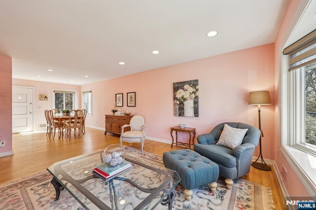 living area featuring baseboards, light wood finished floors, and recessed lighting