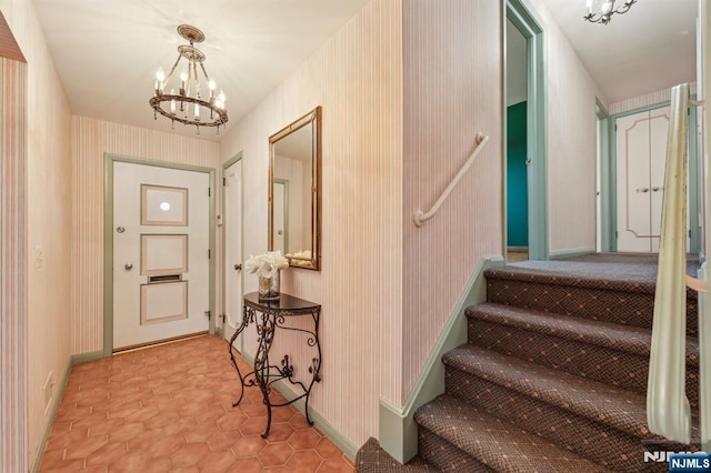 interior space with a chandelier, baseboards, and wallpapered walls