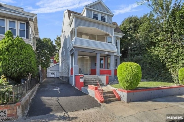 view of front of home with a balcony, fence, and a porch