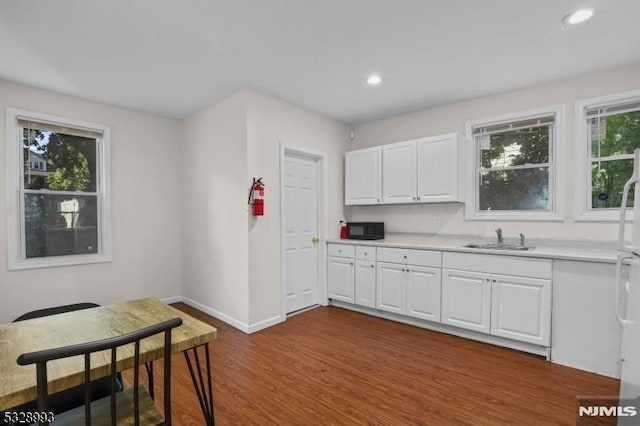 kitchen featuring a sink, baseboards, white cabinets, light countertops, and dark wood-style floors