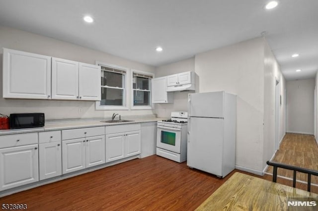 kitchen featuring white appliances, white cabinets, dark wood finished floors, light countertops, and under cabinet range hood