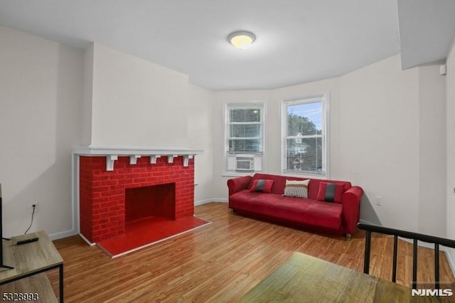 living area with a fireplace, baseboards, and wood finished floors