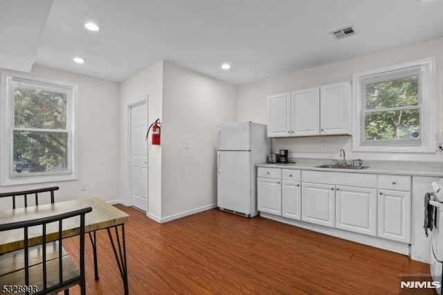 kitchen with visible vents, dark wood-type flooring, freestanding refrigerator, white cabinetry, and a sink