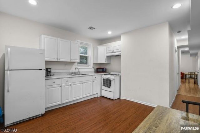 kitchen with white appliances, dark wood-style floors, under cabinet range hood, white cabinetry, and a sink