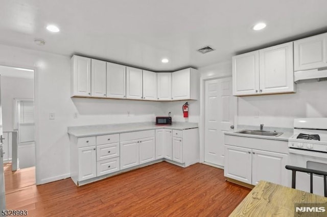 kitchen featuring light wood-style flooring, white range with gas stovetop, visible vents, and light countertops