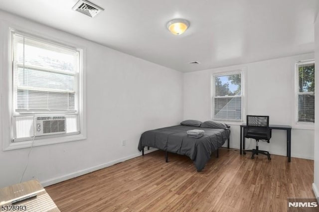 bedroom featuring light wood-type flooring, visible vents, baseboards, and multiple windows