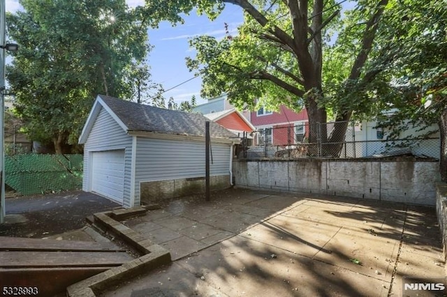 view of patio with an outbuilding, fence, and a detached garage