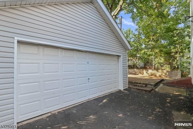 garage with aphalt driveway and fence