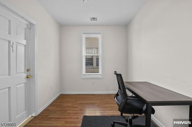 office area featuring baseboards, visible vents, and wood finished floors