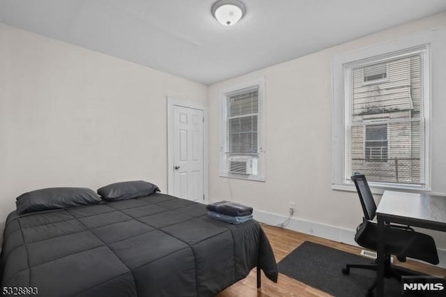 bedroom with light wood-type flooring, cooling unit, and baseboards