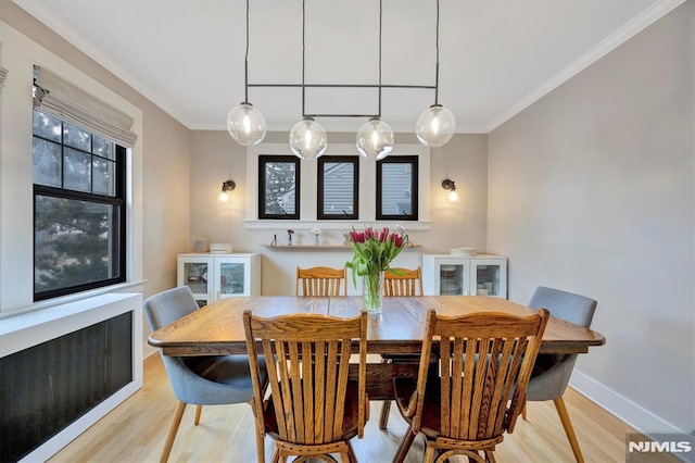 dining area with light wood finished floors, baseboards, and crown molding