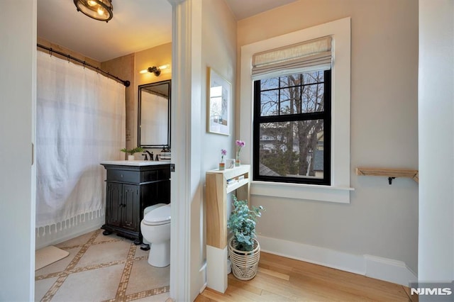 bathroom with toilet, vanity, and baseboards