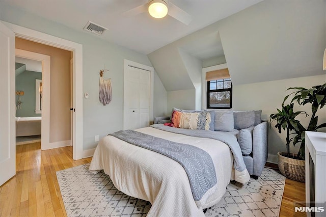 bedroom featuring light wood-style flooring, visible vents, vaulted ceiling, and baseboards