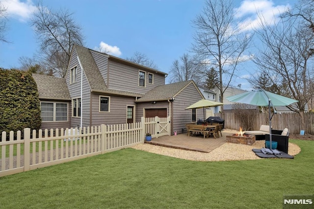 back of property featuring fence private yard, a yard, a fire pit, and roof with shingles