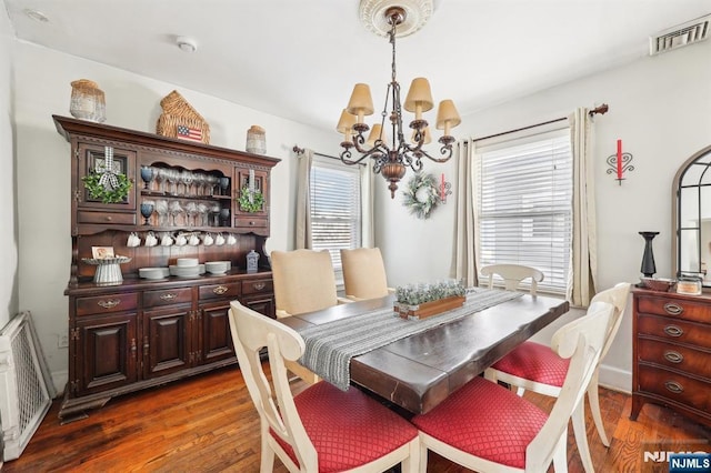 dining space featuring a healthy amount of sunlight, visible vents, a notable chandelier, and wood finished floors