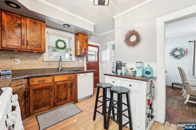 kitchen with stove, white dishwasher, a sink, and light wood-style floors