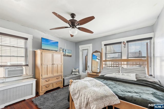 bedroom featuring radiator, multiple windows, dark wood finished floors, and cooling unit