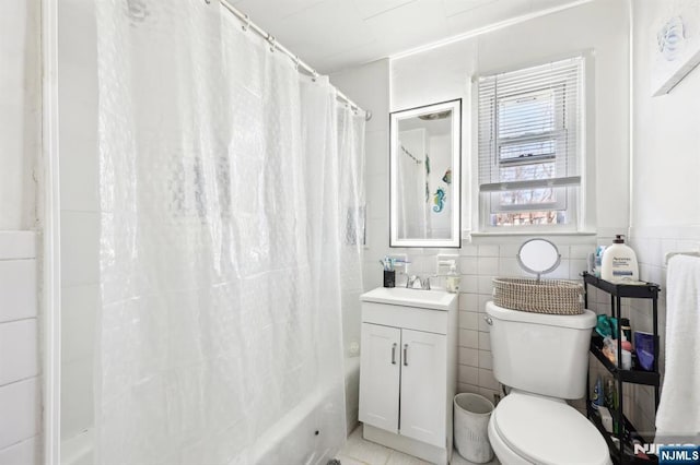 full bathroom with toilet, a wainscoted wall, shower / bathtub combination with curtain, vanity, and tile walls