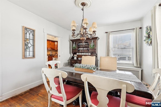 dining room featuring a chandelier, baseboards, and wood finished floors