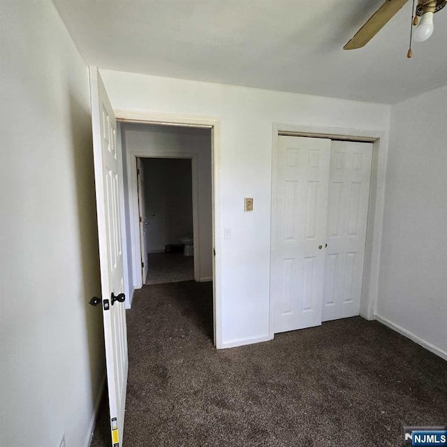 unfurnished bedroom with a ceiling fan, baseboards, dark carpet, and a closet