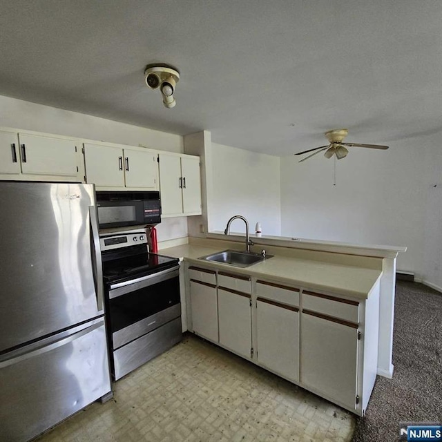 kitchen with stainless steel appliances, a peninsula, a sink, white cabinets, and light countertops