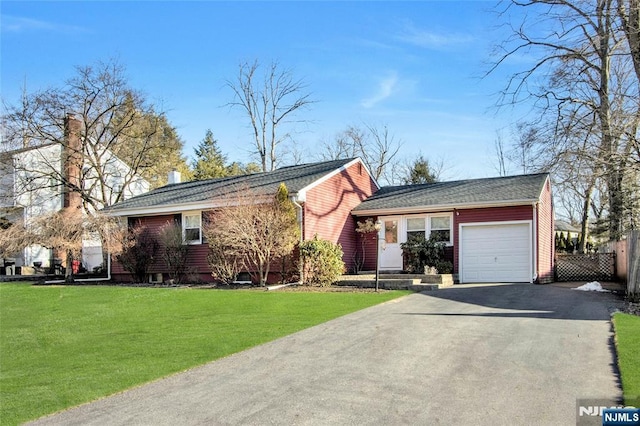 single story home with aphalt driveway, an attached garage, fence, and a front yard