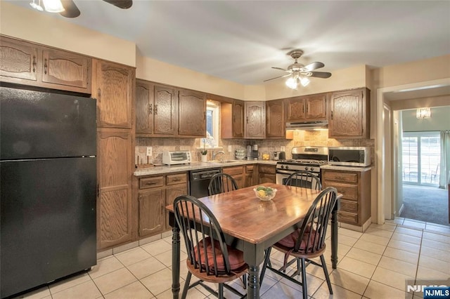 kitchen with black appliances, ceiling fan, under cabinet range hood, and decorative backsplash