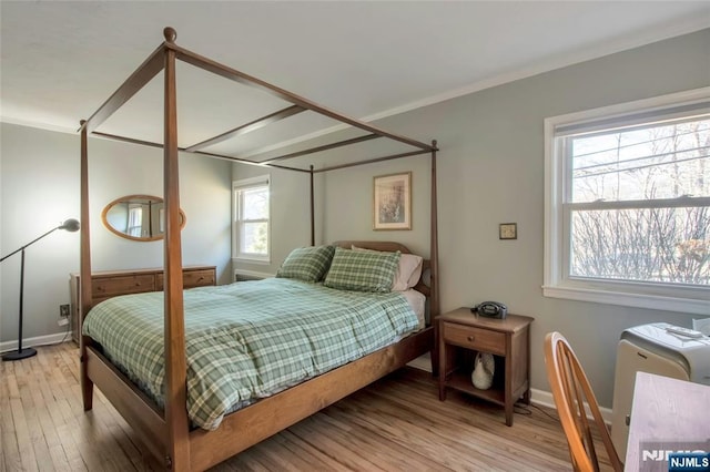 bedroom featuring light wood-style flooring, ornamental molding, and baseboards