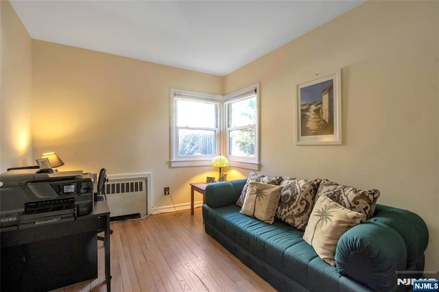 living area with baseboards, hardwood / wood-style floors, and radiator heating unit