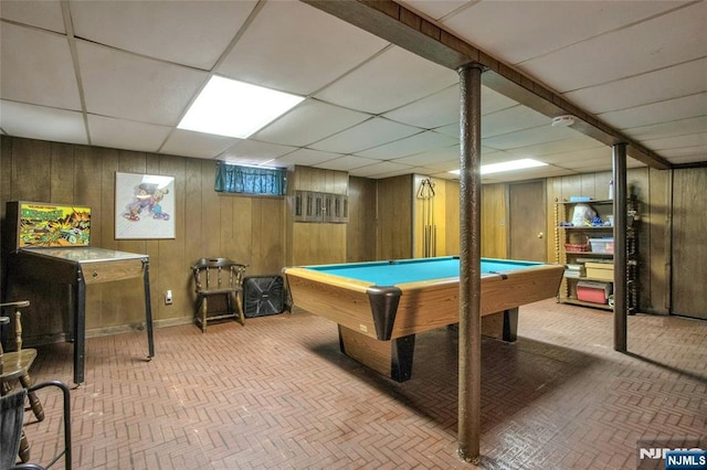 game room featuring a paneled ceiling, pool table, and wood walls