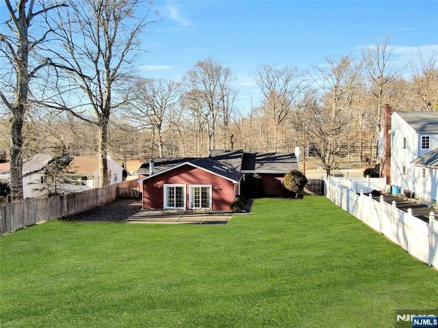 rear view of house featuring a fenced backyard, a lawn, and a patio