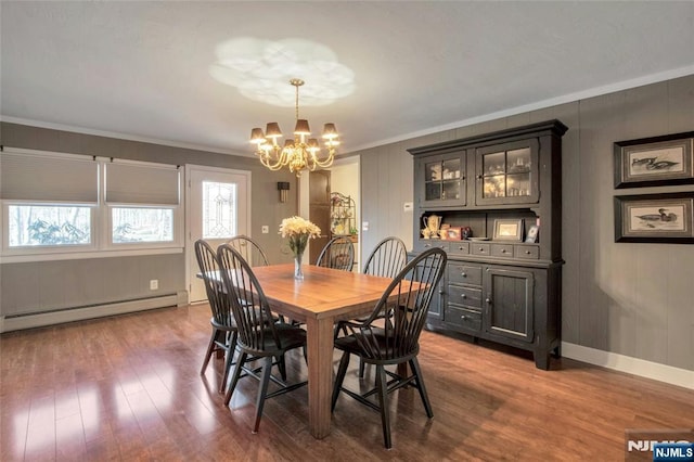 dining space featuring crown molding, a notable chandelier, a baseboard heating unit, wood finished floors, and baseboards