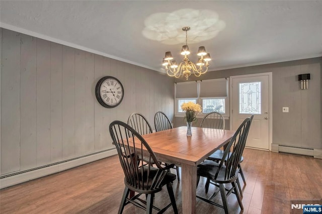 dining room featuring ornamental molding, a baseboard radiator, wood finished floors, and a notable chandelier