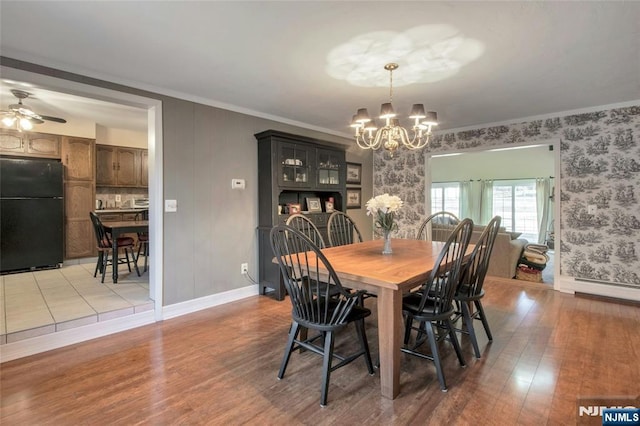 dining area featuring crown molding, a baseboard radiator, light wood-type flooring, baseboards, and ceiling fan with notable chandelier