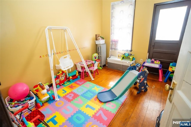 recreation room with radiator heating unit and hardwood / wood-style flooring