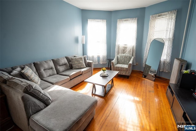 living room with light wood-style floors, radiator heating unit, and arched walkways