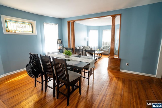 dining space with ornate columns, wood-type flooring, and baseboards