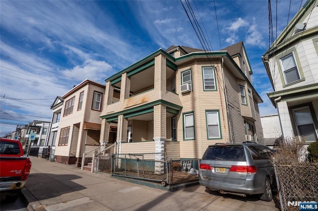 view of front of property with covered porch, a fenced front yard, cooling unit, and a balcony