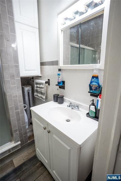 bathroom with a wainscoted wall, wood finished floors, tile walls, and vanity