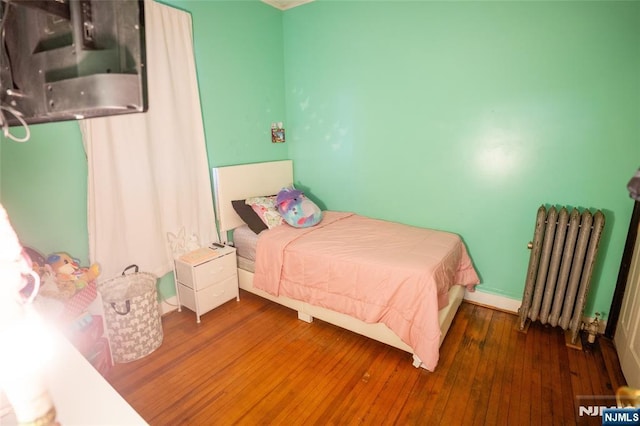 bedroom with hardwood / wood-style floors and radiator heating unit