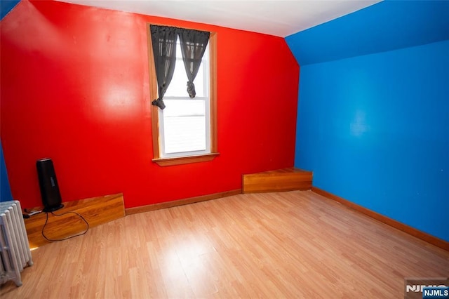 bonus room featuring lofted ceiling, radiator, baseboards, and wood finished floors