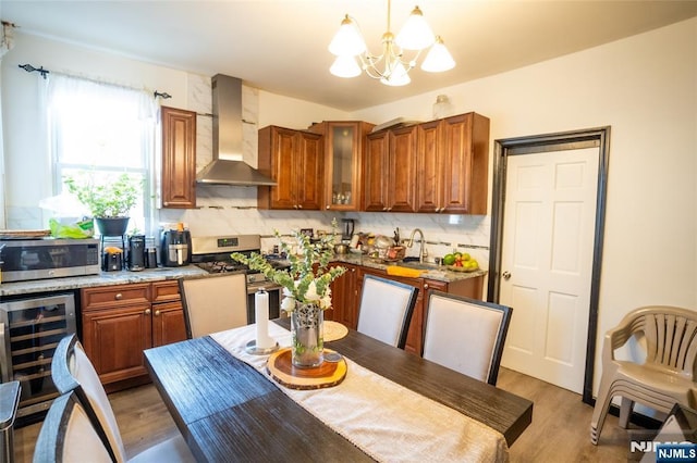 kitchen with appliances with stainless steel finishes, brown cabinets, a sink, and wall chimney exhaust hood