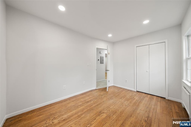 unfurnished bedroom with baseboards, a closet, light wood-type flooring, and recessed lighting