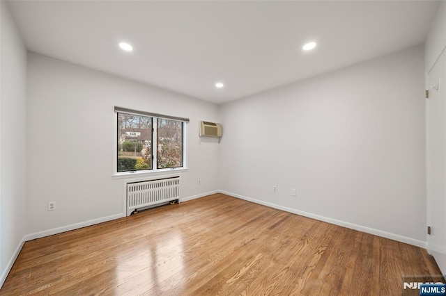 spare room featuring baseboards, recessed lighting, wood finished floors, and radiator