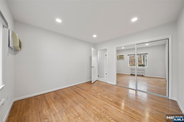 unfurnished bedroom featuring recessed lighting, light wood-style flooring, radiator heating unit, and a wall mounted AC