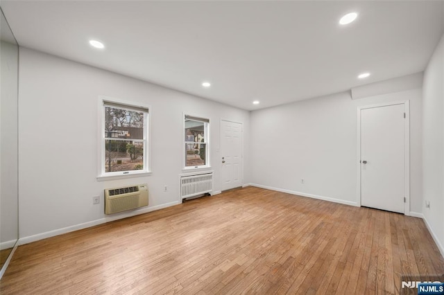 unfurnished room with recessed lighting, a wall mounted air conditioner, light wood-style flooring, and radiator heating unit