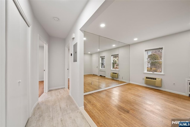 interior space featuring baseboards, a wall mounted air conditioner, an AC wall unit, light wood-type flooring, and recessed lighting