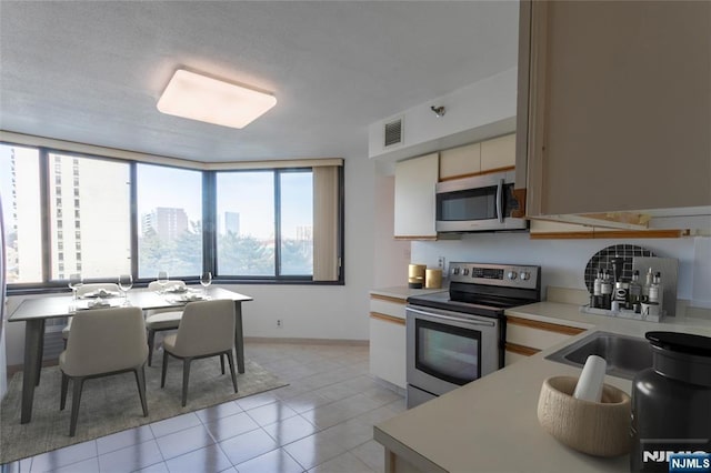kitchen with stainless steel appliances, light countertops, plenty of natural light, and light tile patterned floors
